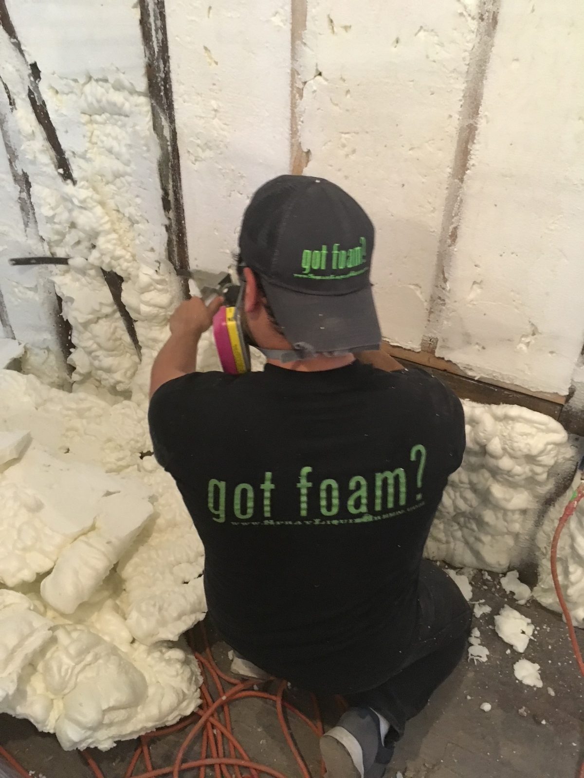 Liquid Green crew member spraying open-cell spray foam in a wall cavity