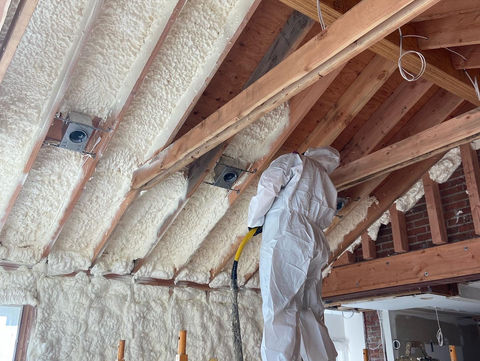 Worker applying insulation in attic