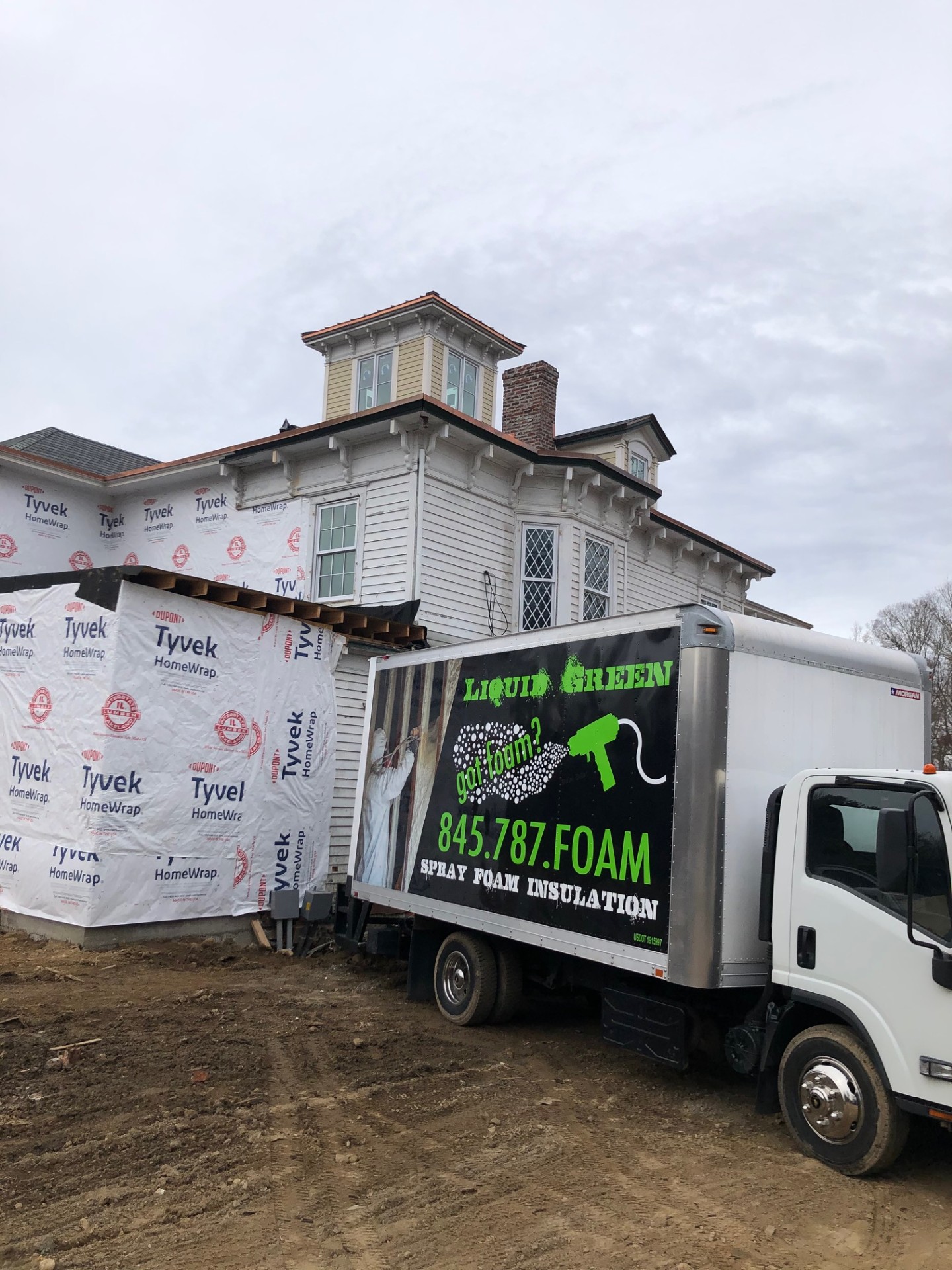 Liquid Green truck at a Victorian-style home with Tyvek wrap
